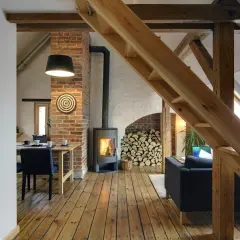 Przytulny strych z palącym się kominkiem, drewnianymi belkami i widokiem na jadalnię.