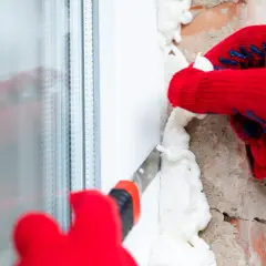 Rękawiczki w czerwonym kolorze pomagają usunąć nadmiar pianki montażowej. Narzędzie do cięcia pianki jest używane do precyzyjnego wykończenia.