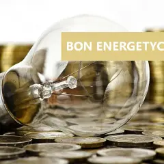 Żarówka na stosach monet. Napis "BON ENERGETYCZNY" sugeruje, że dotyczy on wsparcia finansowego dla osób potrzebujących.