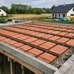 Budowa domu w toku: strop gęstożebrowy z pustaków ceramicznych i zbrojenia, gotowy do zalania betonem.