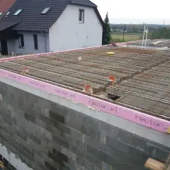 Budowa stropu zbrojonego, widoczna izolacja z różową pianką z napisem rector.pl, przygotowania do wylania betonu.