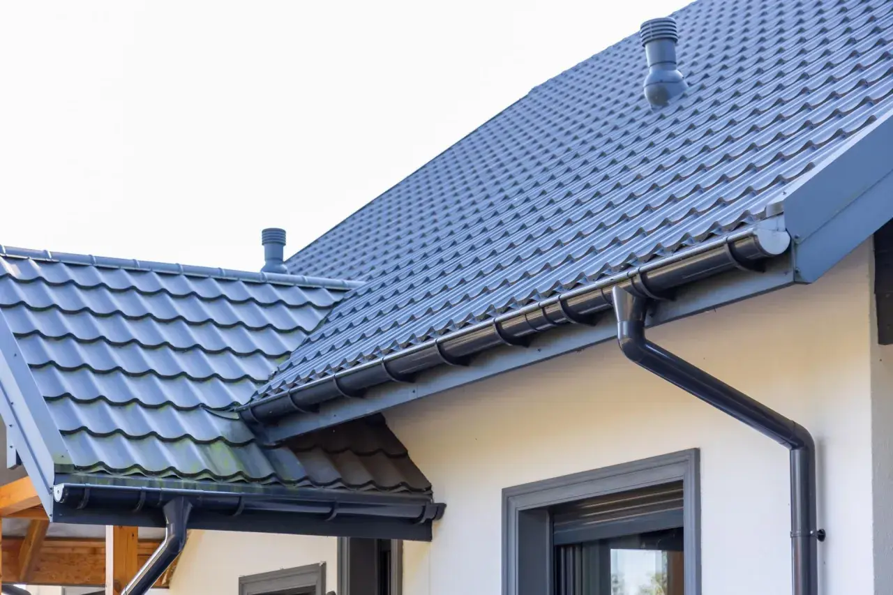 Szary dach z dachówki ceramicznej, rynny i kominek. Sprawdź, jaka jest dachówka ceramiczna cena za m2.